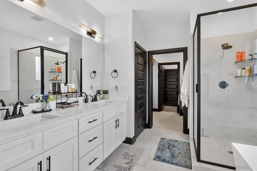 Contemporary bathroom featuring a double vanity with white cabinetry, light-toned countertops, and matte black fixtures
