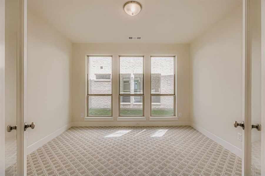 Spare room featuring light carpet, plenty of natural light, and french doors Spare room featuring light carpet, plenty of natural light, and french doors