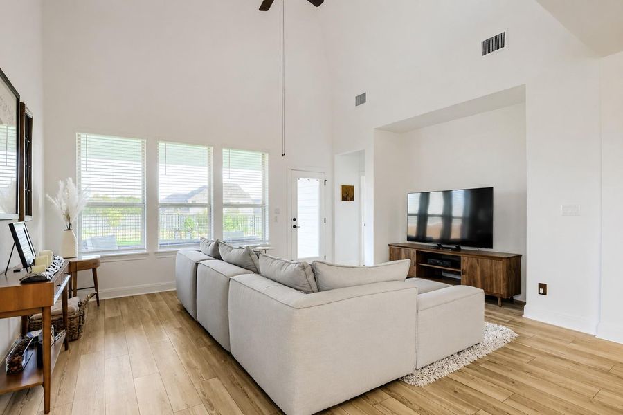 A spacious living room features soaring ceilings, wooden floors, and ample natural light. A spacious living room features soaring ceilings, wooden floors, and ample natural light.