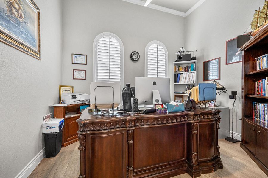 Elegant home office featuring arched windows, rich wood flooring, and extensive built-in storage for a productive workspace. Elegant home office featuring arched windows, rich wood flooring, and extensive built-in storage for a productive workspace.