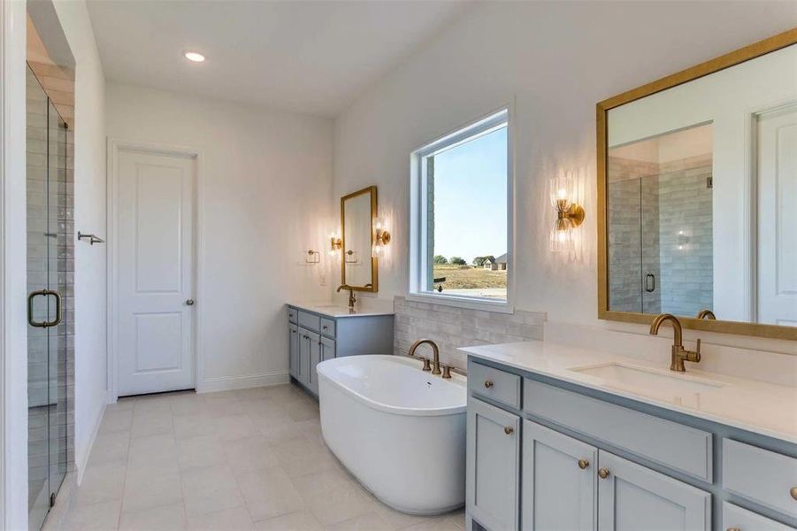 Bathroom featuring a stall shower, a soaking tub, two vanities, recessed lighting, and light tile patterned flooring Bathroom featuring a stall shower, a soaking tub, two vanities, recessed lighting, and light tile patterned flooring