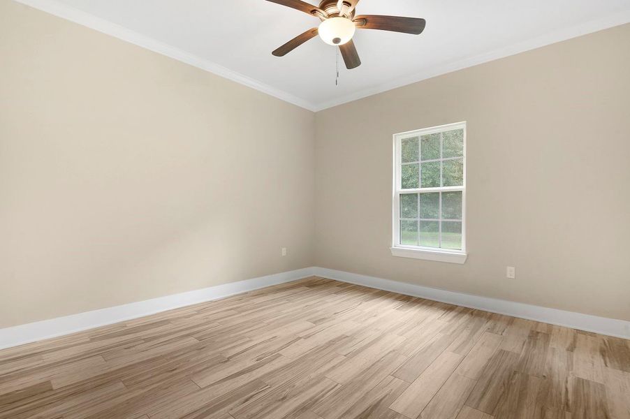 This room features neutral-colored walls, light wood flooring, a ceiling fan with lighting, and a window that lets in natural light, creating a bright and inviting atmosphere. This room features neutral-colored walls, light wood flooring, a ceiling fan with lighting, and a window that lets in natural light, creating a bright and inviting atmosphere.