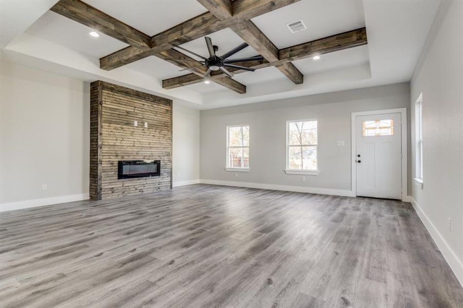 Unfurnished living room with light hardwood / wood-style floors, beam ceiling, and coffered ceiling