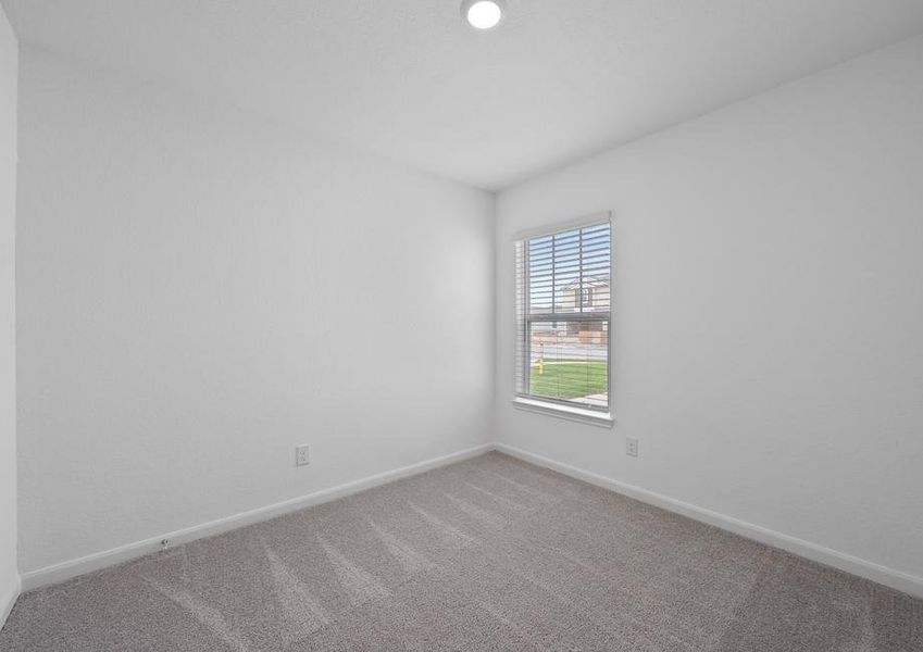 Secondary bedroom with tan carpet and a window.