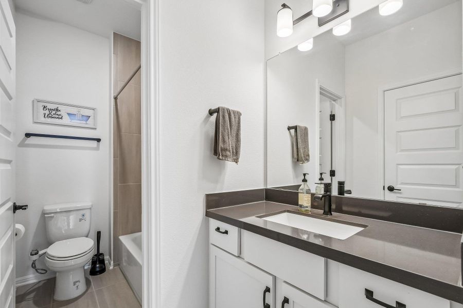 Modern full bathroom with a spacious vanity, sleek black fixtures, and a tiled tub and shower combination.