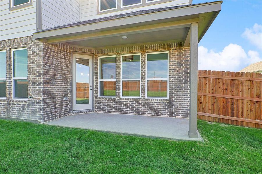 Property entrance with a patio area and a lawn