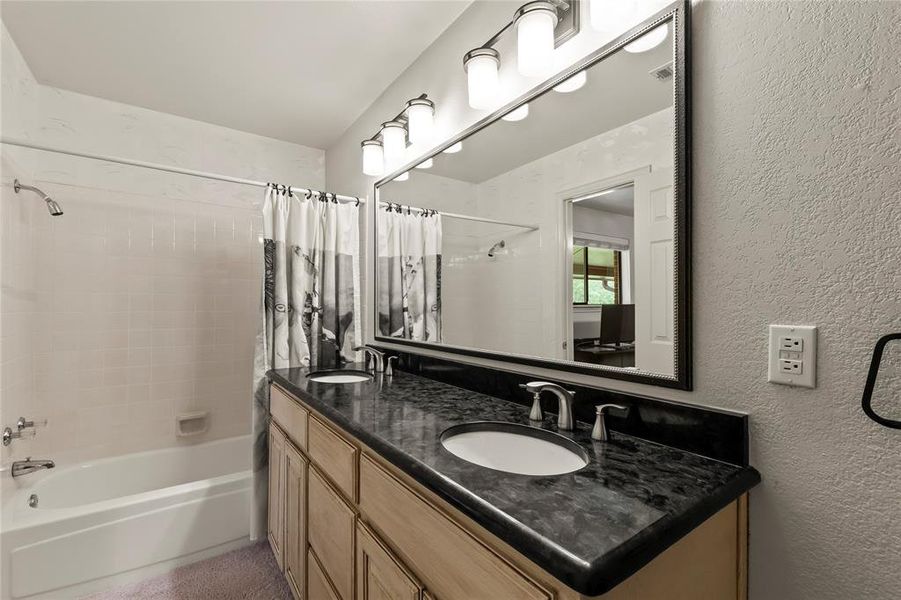 Soaking bathtub in the primary bathroom with double sink vanity.