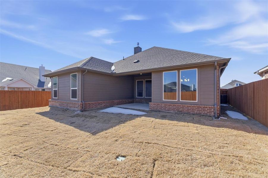 Rear view of house featuring a fenced backyard, a patio, brick siding, roof with shingles, and a chimney