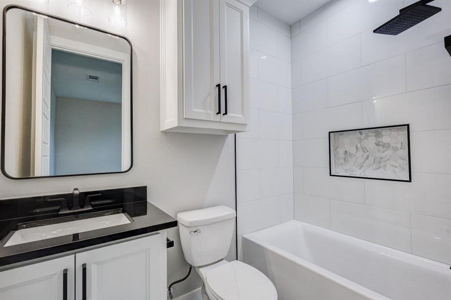 Bathroom featuring a white vanity with black hardware, a black countertop, and an undermount sink