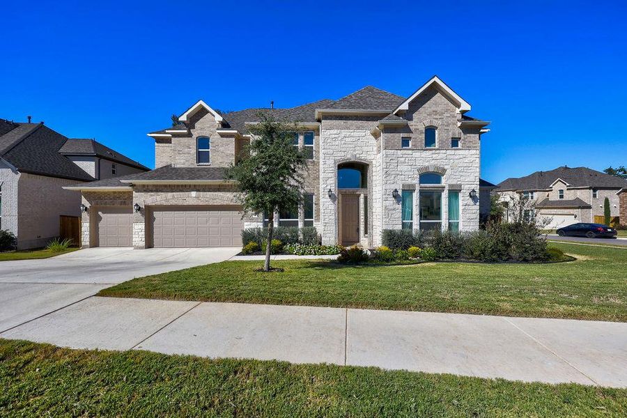 French provincial home with driveway, a front lawn, stone siding, a garage, and brick siding