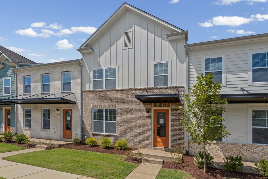 Contemporary exterior featuring board and batten siding, brick façade, and an orange entry door