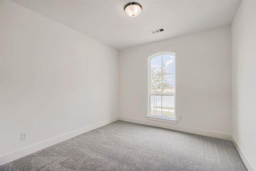 Interior space featuring an arched window, light gray carpet, white walls, and a semi-flush mount ceiling light
