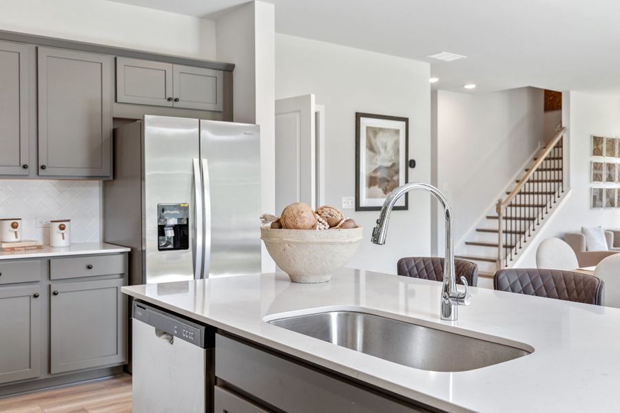 A kitchen with a sink and a refrigerator. A kitchen with a sink and a refrigerator.