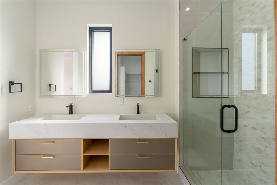 Full bathroom featuring double vanity, a shower stall, and light tile patterned floors Full bathroom featuring double vanity, a shower stall, and light tile patterned floors
