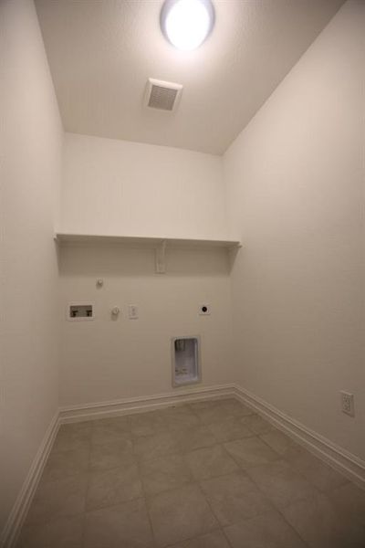 Dedicated utility space featuring tile flooring, white baseboards, a built-in shelf, overhead lighting, and a ceiling ventilation fan