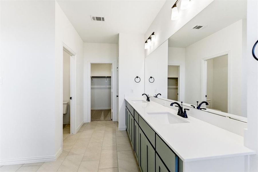 Full bath featuring a spacious closet and double vanity