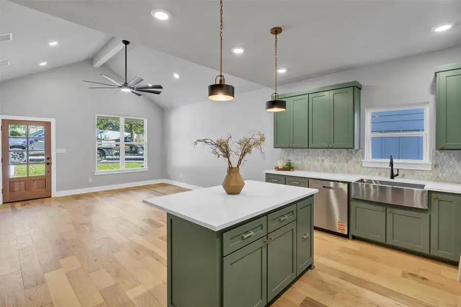 Kitchen featuring green cabinetry, a center island, hanging light fixtures, light wood-style flooring, and ceiling fan