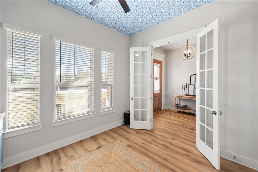 Spare room featuring french doors, light wood finished floors, and a fan