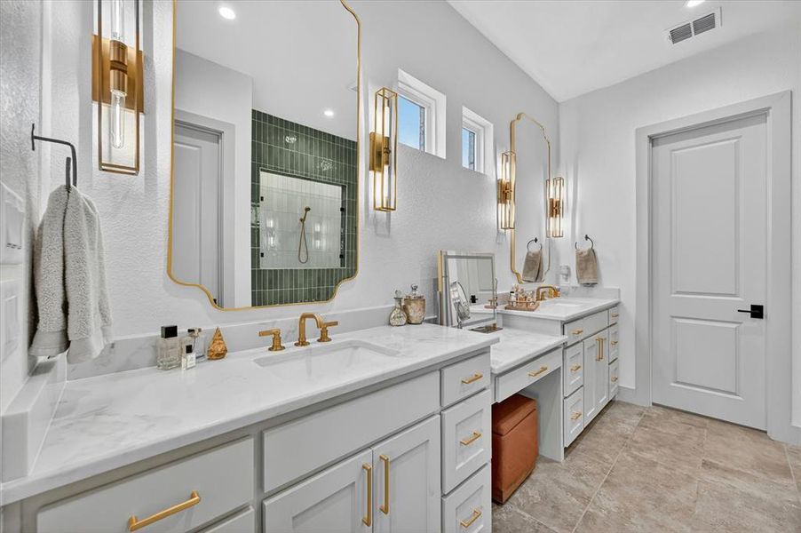 Dual vanity with white cabinetry, light stone-finish countertops, and gold-finish hardware