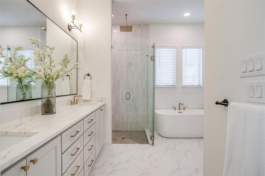 Primary Bathroom featuring vanity with dual sinks, gold hardware, tile flooring and walk in shower with two shower heads including rain fall.