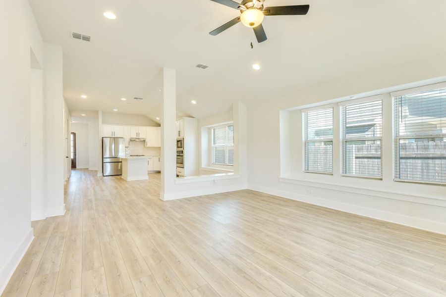 Unfurnished living room with vaulted ceiling, light wood-type flooring, recessed lighting, and a ceiling fan