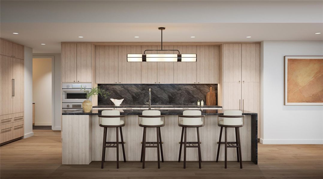 Kitchen in Twilight palette featuring a large breakfast bar, designer lighting, wood flooring, recessed lights, and natural stone quartzite countertops. Includes a full Thermador appliance suite with refrigerator, induction cooktop, wall oven, dishwasher, and built-in wine preservation tower. Contrasting dark quartzite backsplash and light cabinetry provide a modern, dramatic balance. Representative finish shown; three palettes available, design varies by residence. Kitchen in Twilight palette featuring a large breakfast bar, designer lighting, wood flooring, recessed lights, and natural stone quartzite countertops. Includes a full Thermador appliance suite with refrigerator, induction cooktop, wall oven, dishwasher, and built-in wine preservation tower. Contrasting dark quartzite backsplash and light cabinetry provide a modern, dramatic balance. Representative finish shown; three palettes available, design varies by residence.