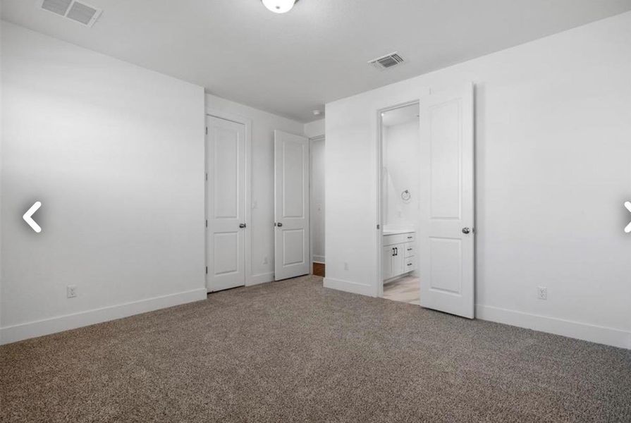 Unfurnished bedroom featuring light carpet, ensuite bath, and a closet