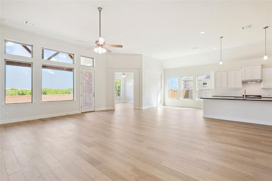 Unfurnished living room featuring sink, plenty of natural light, ceiling fan, and light hardwood / wood-style floors