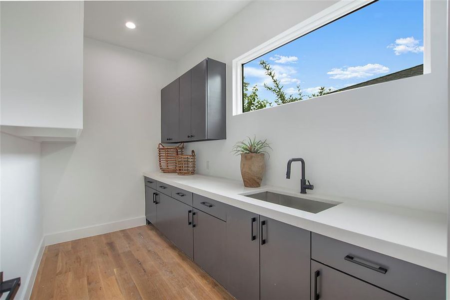 Kitchen with gray cabinets, light wood-type flooring, and sink