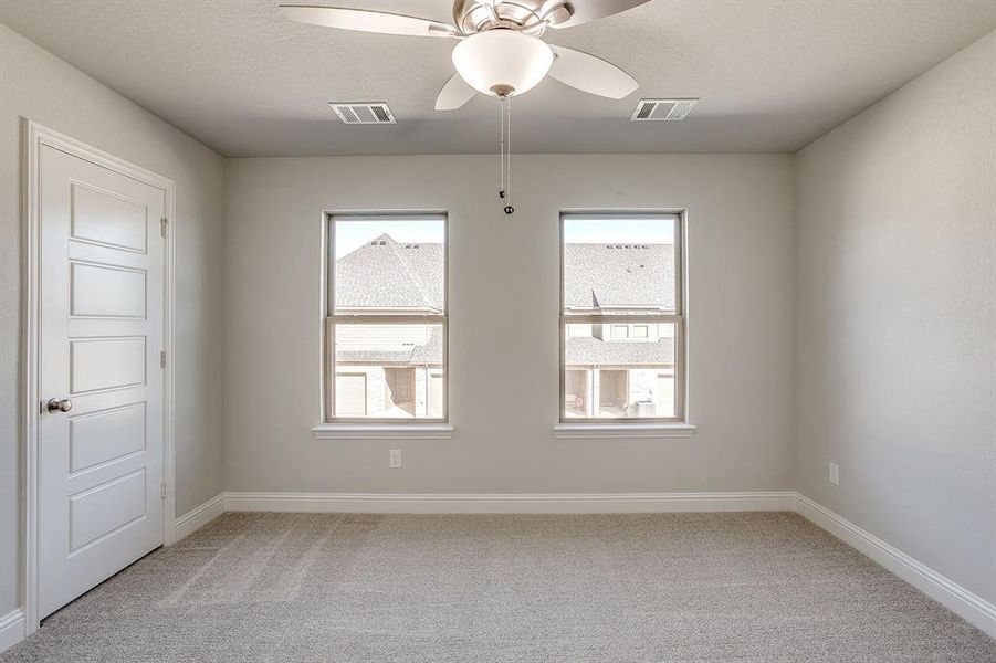 Empty room with a ceiling fan, light carpet, and a textured ceiling