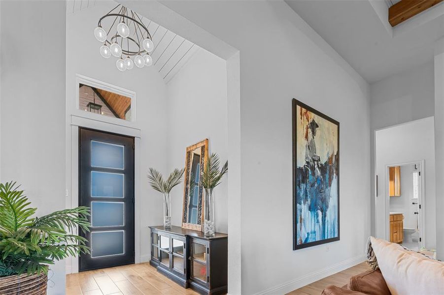 Entryway with light wood-type flooring, high vaulted ceiling, and a chandelier