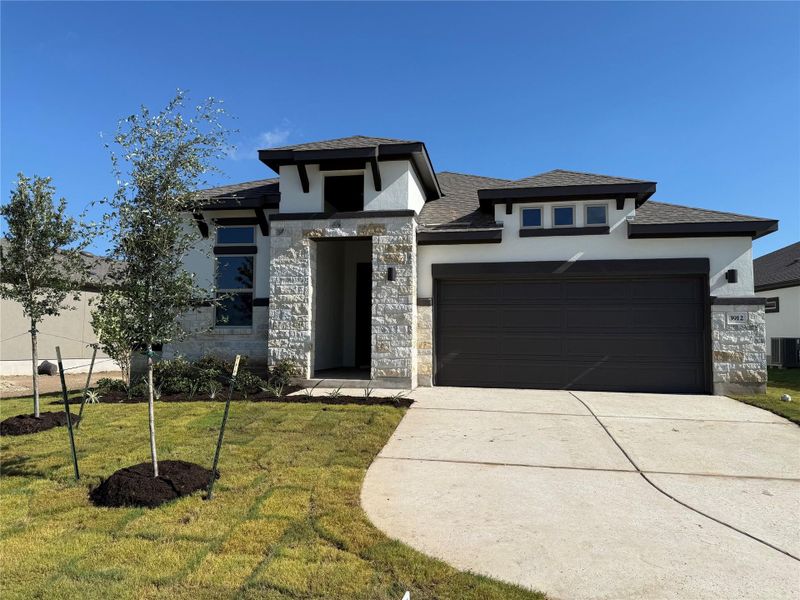 View of front of home featuring stone siding, a garage, stucco siding, driveway, and a front yard View of front of home featuring stone siding, a garage, stucco siding, driveway, and a front yard