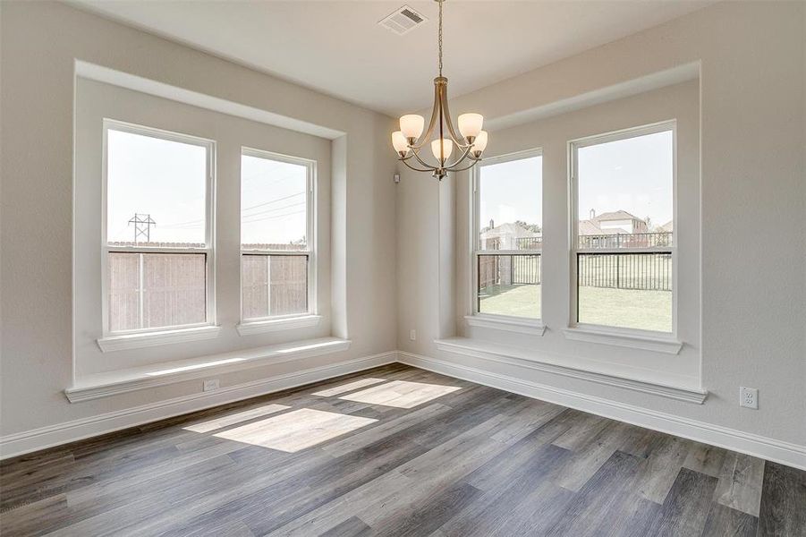 Empty room featuring dark hardwood / wood-style flooring and a notable chandelier