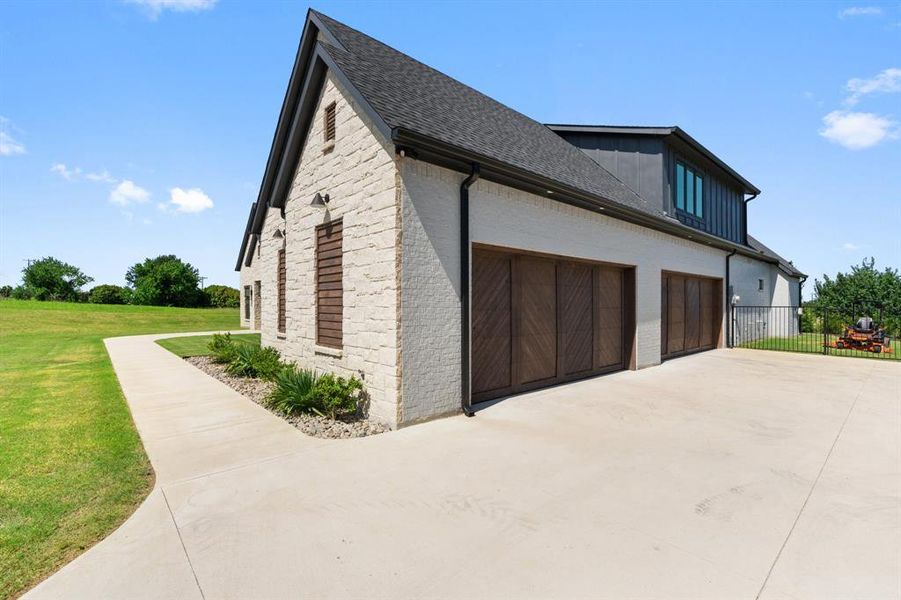 View of side of property featuring a garage and a lawn