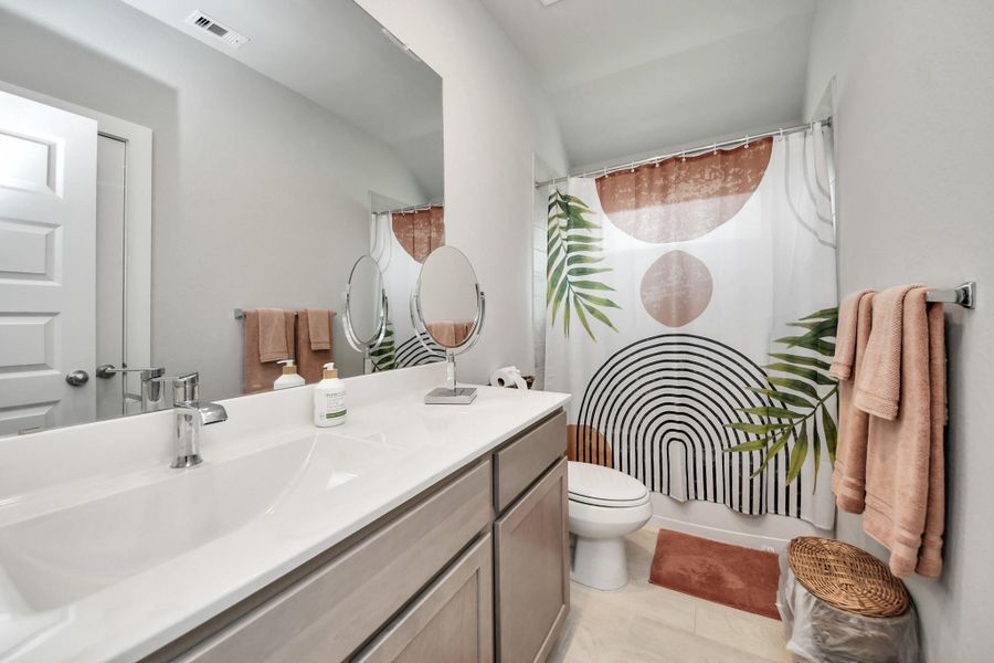 Clean lines and functional elegance define this full bath, anchored by an expansive vanity and wide plate-glass mirror.