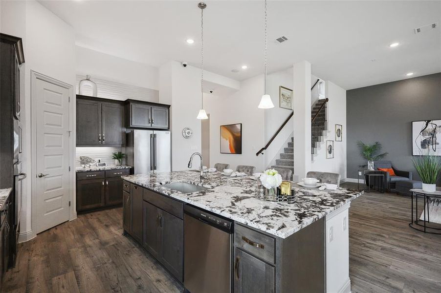 Kitchen with appliances with stainless steel finishes, dark hardwood / wood-style flooring, a kitchen island with sink, sink, and tasteful backsplash