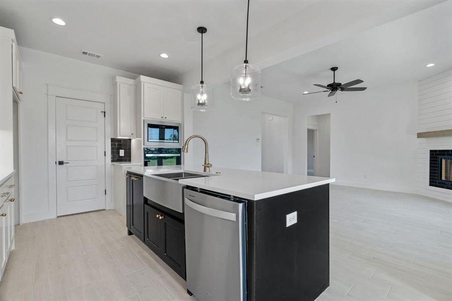 Kitchen with open floor plan, light countertops, a fireplace, a ceiling fan, and recessed lighting