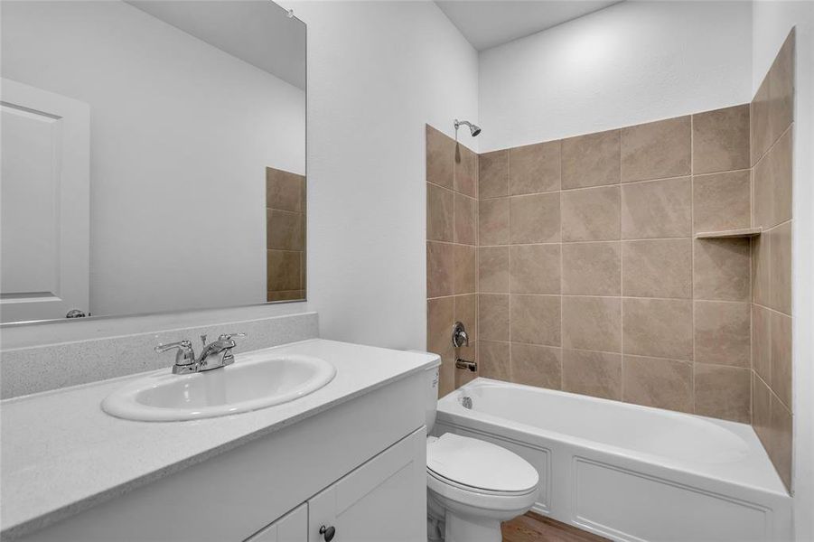 Full bathroom with vanity, tiled shower / bath combo, and toilet