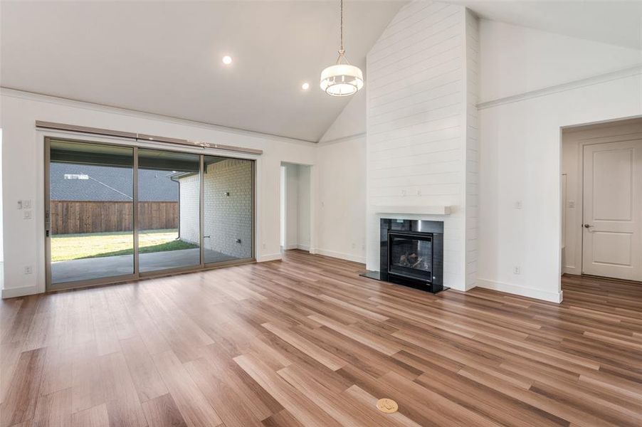 Expansive living room featuring high vaulted ceiling, wood finished floors, a large fireplace, and recessed lighting Expansive living room featuring high vaulted ceiling, wood finished floors, a large fireplace, and recessed lighting