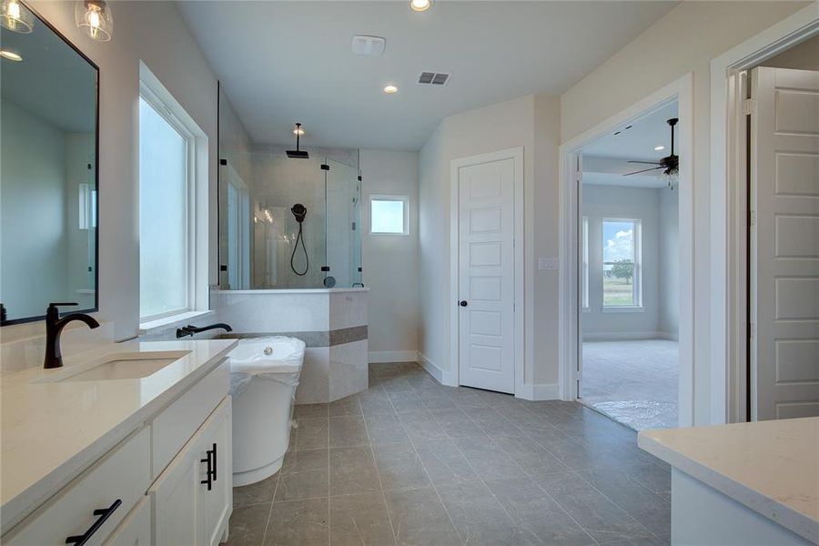 Bathroom with tiled shower, oversized vanity, dual sinks, ceiling fan, and tile flooring