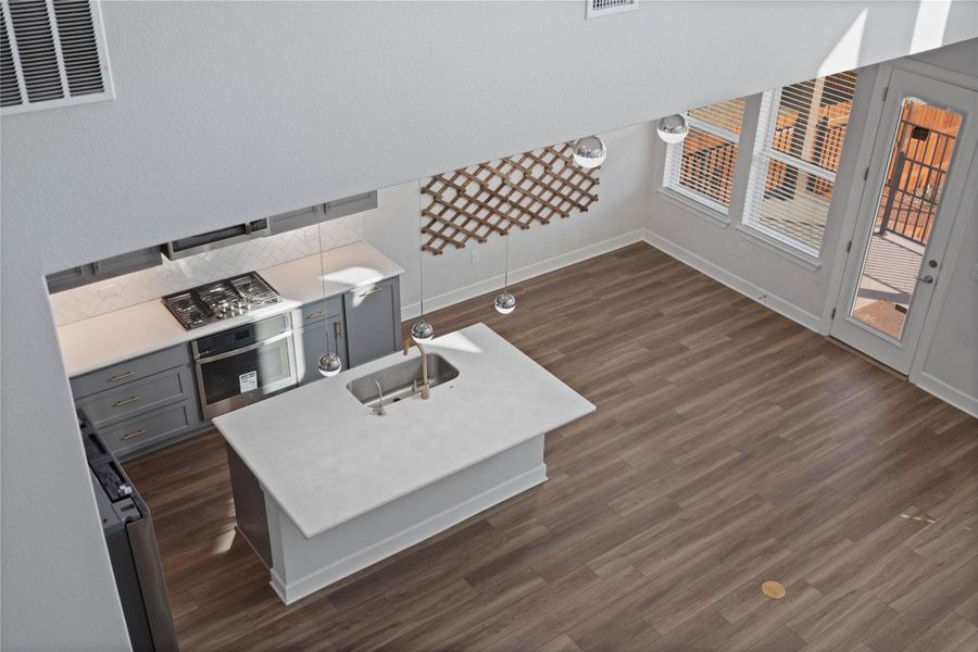 An open kitchen layout transitions into a light-filled living area featuring clean wood flooring.