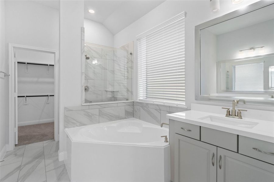 This luxurious primary bathroom serves as a spa-like retreat, boasting a deep, separate soaking tub perfect for relaxation and a dedicated walk-in shower for convenience. The dual vanity features sleek light gray cabinetry and pristine white countertops, providing ample space for two. This luxurious primary bathroom serves as a spa-like retreat, boasting a deep, separate soaking tub perfect for relaxation and a dedicated walk-in shower for convenience. The dual vanity features sleek light gray cabinetry and pristine white countertops, providing ample space for two.