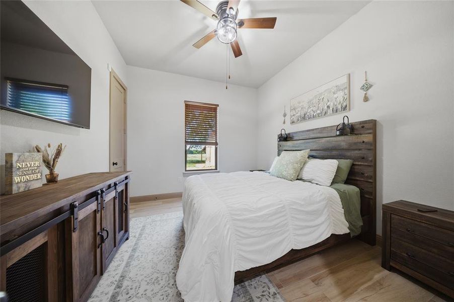Spacious room featuring vaulted ceilings, wood-finish flooring, a window with wood blinds, and a ceiling fan with light fixture