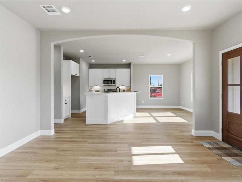 Kitchen featuring white cabinetry, light countertops, light wood-style floors, a kitchen island with sink, and recessed lighting Kitchen featuring white cabinetry, light countertops, light wood-style floors, a kitchen island with sink, and recessed lighting