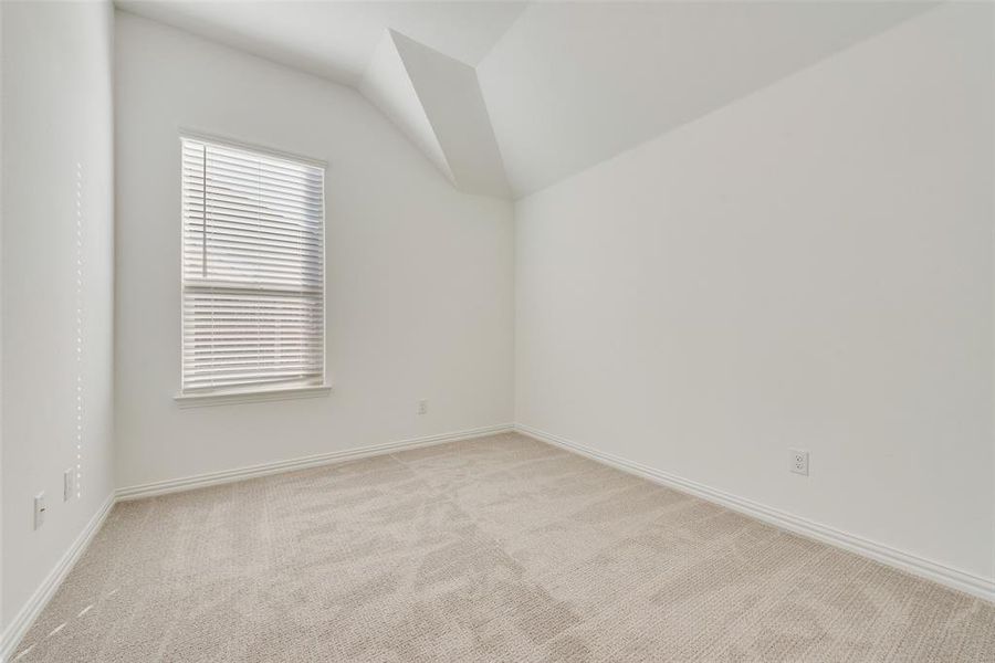 Unfurnished room featuring light carpet and lofted ceiling