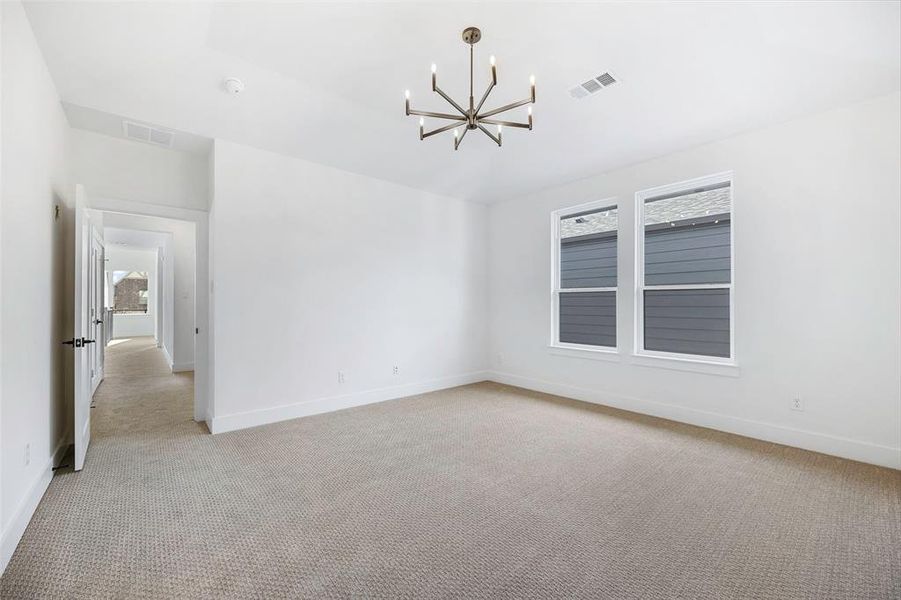 Unfurnished room featuring an inviting chandelier, baseboards, visible vents, and light colored carpet