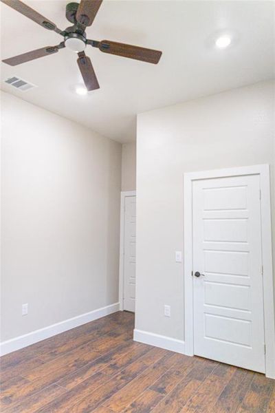 Unfurnished room featuring dark wood-style flooring and a ceiling fan Unfurnished room featuring dark wood-style flooring and a ceiling fan