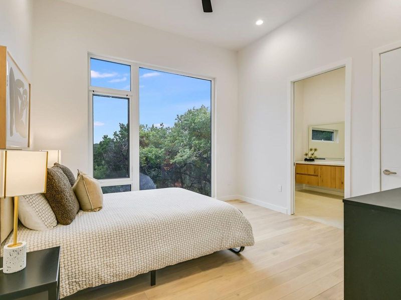 Floor-to-ceiling windows offer serene outdoor vistas from this inviting sleeping space. Floor-to-ceiling windows offer serene outdoor vistas from this inviting sleeping space.