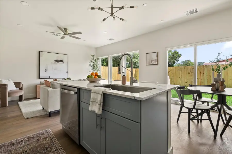 A contemporary kitchen island with a deep sink anchors this open-concept living space, illuminated by sliding glass doors.