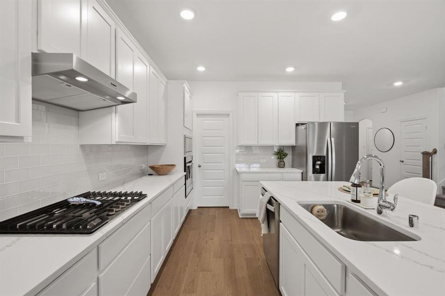 Bright white chef’s kitchen with quartz countertops, gas cooktop, stainless appliances, and a large island perfect for everyday living and entertaining.